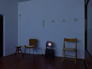 渡辺泰子「We are tilting.」上映風景。椅子の背後の壁に複数点フェルト作品が展示されている。